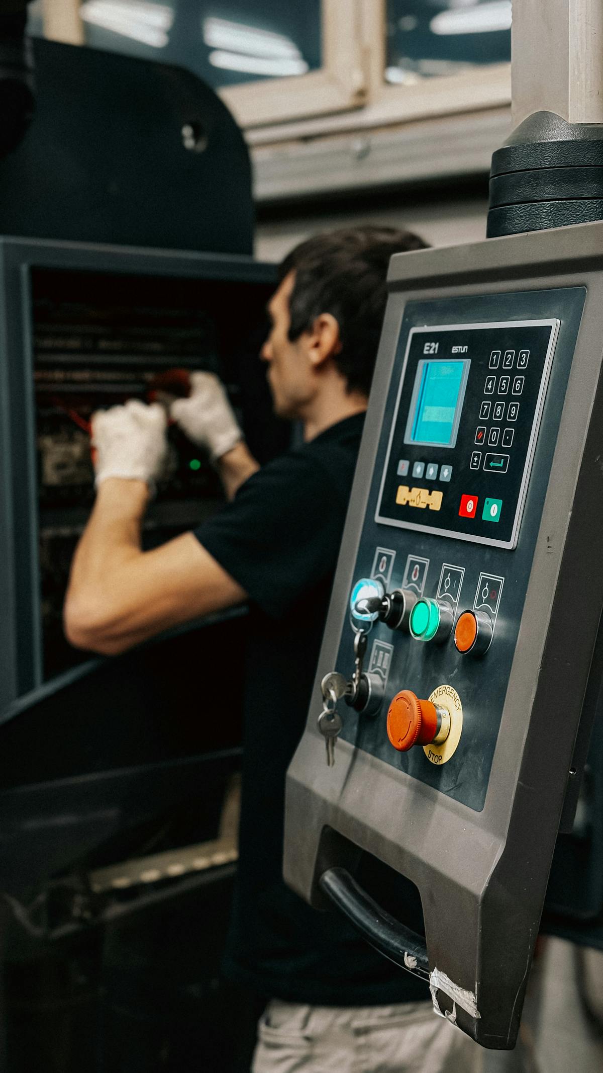 Technician working beside an industrial machine control panel